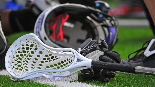 A lacrosse stick and helmet rest on the grass near a white field line in this lacrosse scene, HD Desktop Wallpaper