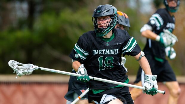 A lacrosse player wearing a helmet and Dartmouth uniform is running with a lacrosse stick on the field, HD Desktop Wallpaper