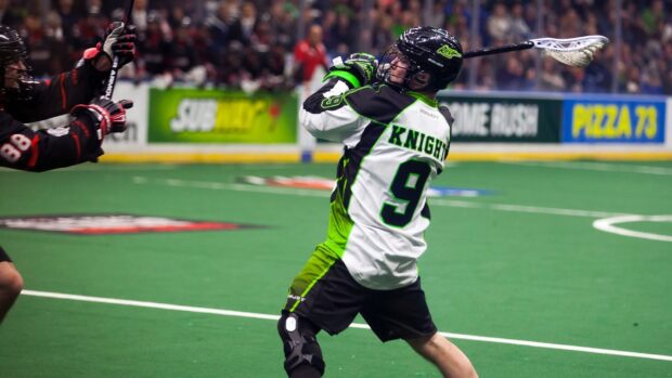 A lacrosse player wearing a white and green jersey is preparing to throw the ball in a competitive match, HD Desktop Wallpaper