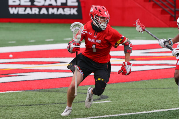 A lacrosse player in a red Maryland uniform is preparing to pass the ball on the field, 2K Desktop Wallpaper