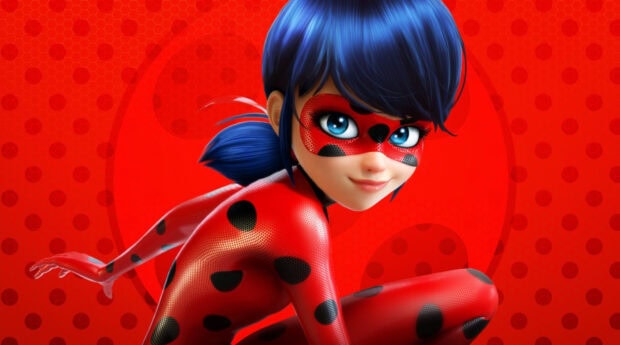 A close up of ladybug character from ladybug and cat noir in a red suit with black spots on a red background