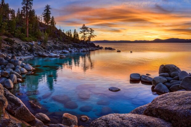 The Lake Tahoe Emerald Bay shows clear water and rocky shore under a colorful sunset sky, HD Desktop Wallpaper