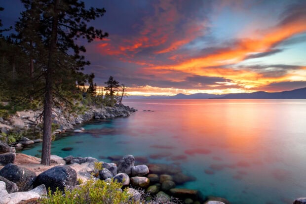 The Lake Tahoe Emerald Bay reveals vibrant colors at sunset with clear water and rocky shore, HD Desktop Wallpaper