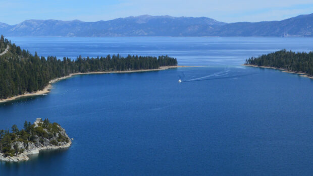 A boat sails across Lake Tahoe Emerald Bay surrounded by forested shores and mountains, HD Desktop Wallpaper