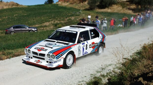 A Lancia car is racing on a dirt road with spectators watching nearby, HD Desktop Wallpaper