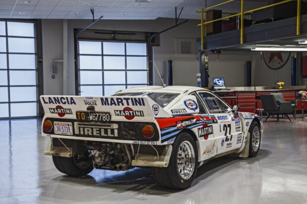 A Lancia rally car with Martini decals is parked inside a modern garage, 2K Desktop Wallpaper