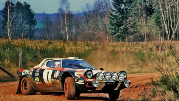 A Lancia rally car speeds along a rural dirt road surrounded by trees and grass, HD Desktop Wallpaper