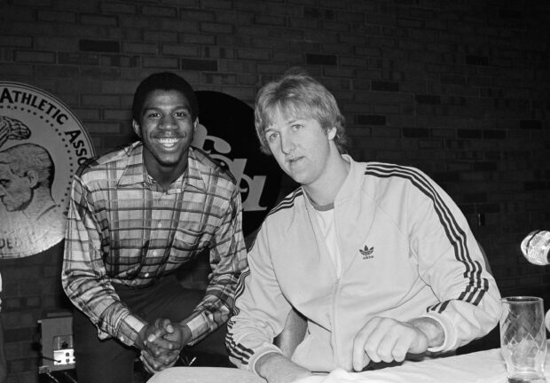 Larry Bird and athlete smiling in a casual setting with a brick wall background, 2K Desktop Wallpaper