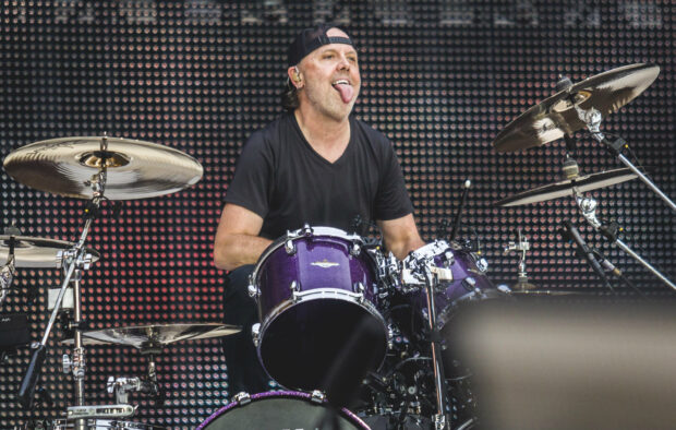 Lars Ulrich is performing energetically on the drum set during a live concert, HD Desktop Wallpaper