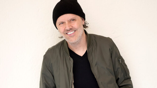 Lars Ulrich is wearing a black beanie and green jacket while smiling at the camera, 2K Desktop Wallpaper