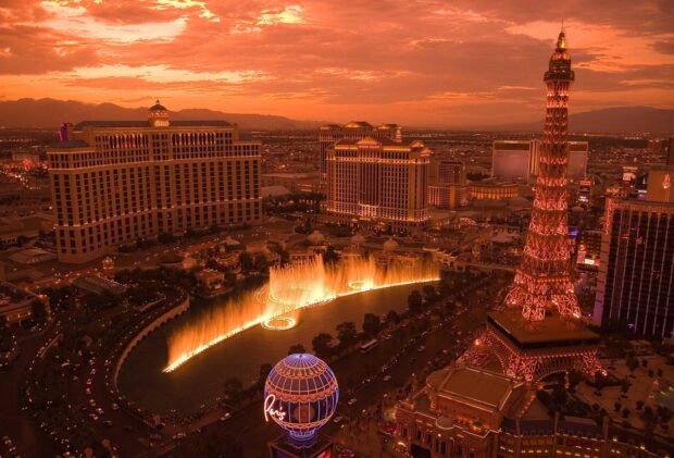 The Las Vegas skyline with fountains and illuminated Eiffel Tower replica at sunset