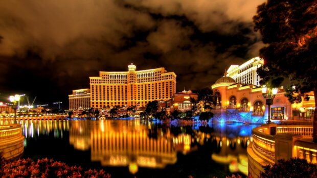 The Las Vegas skyline features illuminated buildings reflecting on the water at night