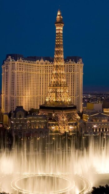 The illuminated replica of the Eiffel Tower in the Las Vegas skyline with fountains lit at night