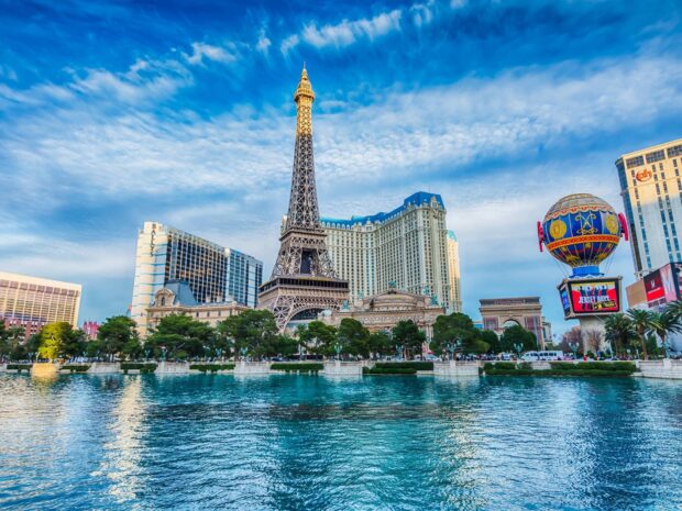 The Las Vegas skyline features the iconic Eiffel Tower replica and vibrant cityscape under a bright blue sky