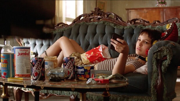 A young woman lounges on a vintage couch surrounded by snacks in Leon Wallpapers, HD Desktop Wallpaper