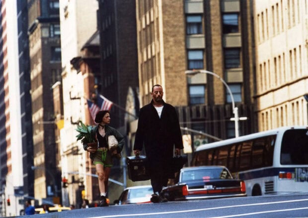 Leon Wallpapers feature two people walking in a busy urban area with tall buildings, 2K Desktop Wallpaper