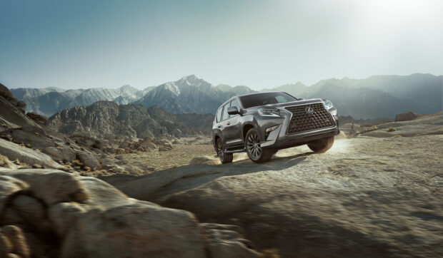 A Lexus GX driving on a rugged rocky landscape with mountains in the background, 2K Desktop Wallpaper