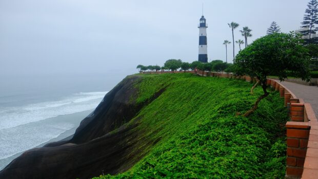 A lighthouse stands on green cliffs overlooking the ocean in Lima Peru, HD Desktop Wallpaper