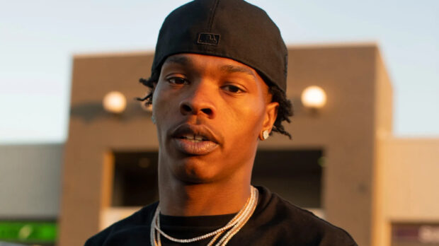 Lil Baby is looking focused standing outdoors with a baseball cap and chains, HD Desktop Wallpaper
