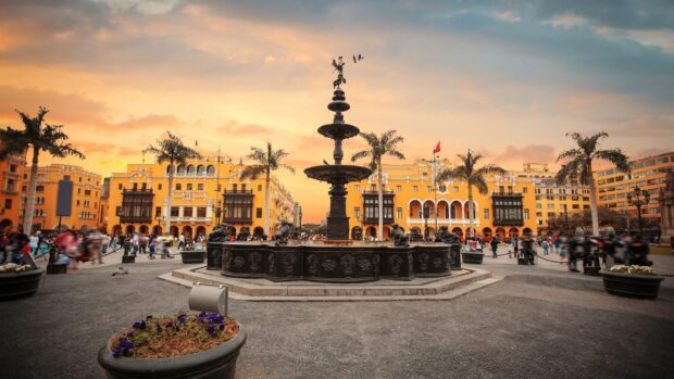 The Lima Peru city center features a large fountain with historic buildings and palm trees at sunset, 2K Desktop Wallpaper