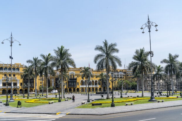 The Lima Peru city center shows palm trees and historic yellow buildings under a clear sky, HD Desktop Wallpaper