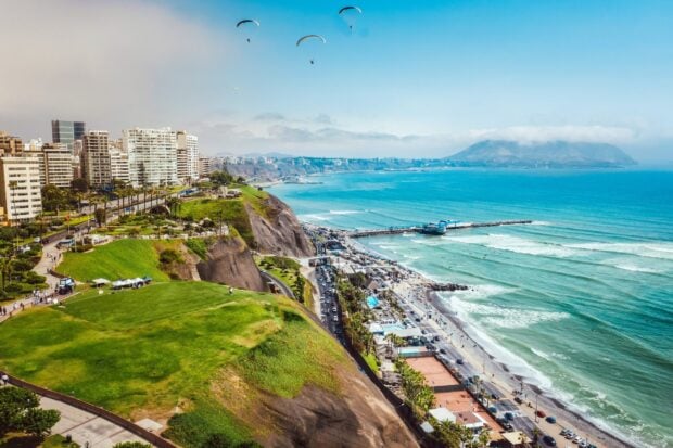 A panoramic view of Lima Peru coastal city with buildings, green cliffs, and the ocean, HD Desktop Wallpaper