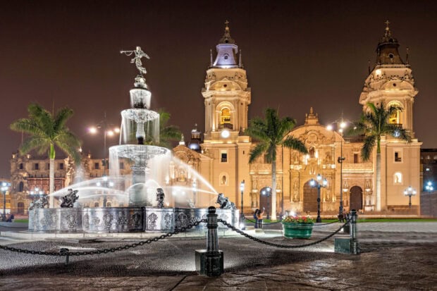 The Lima Peru fountain glows brilliantly in front of the illuminated cathedral at night, 2K Desktop Wallpaper