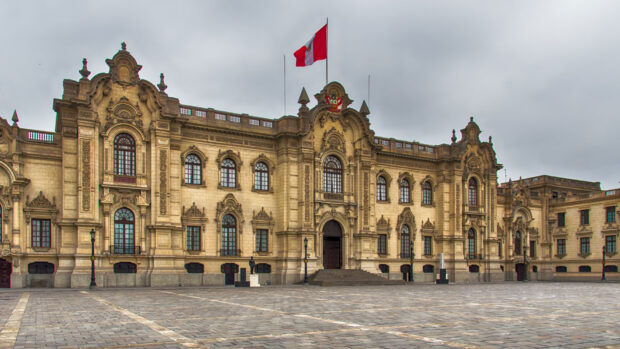 The historical government building in Lima Peru stands under a cloudy sky with a flag above, HD Desktop Wallpaper