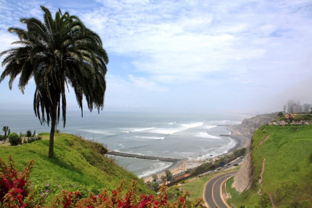 A scenic coastal view in Lima Peru shows cliffs, ocean, and greenery under a cloudy sky, HD Desktop Wallpaper