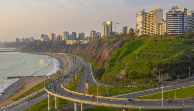 The Lima Peru Wallpapers show a coastal road winding along cliffs under a cloudy sky, HD Desktop Wallpaper