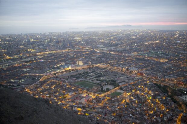 The Lima Peru cityscape shows urban lights glowing against a cloudy sky at dusk, HD Desktop Wallpaper