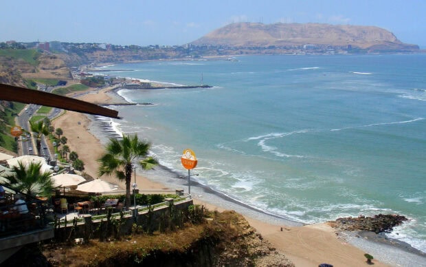 A scenic coastal view of Lima Peru shows cliffs and blue ocean waves under clear skies, 2K Desktop Wallpaper
