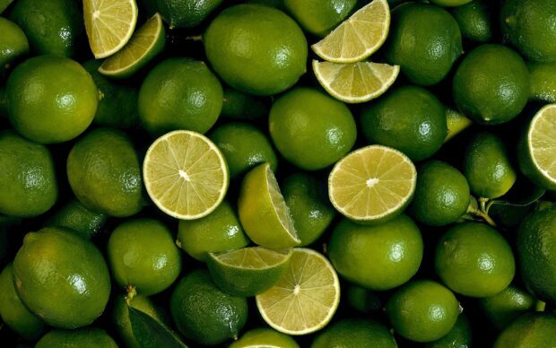 Fresh lime fruit arranged with some cut pieces showing juicy interiors