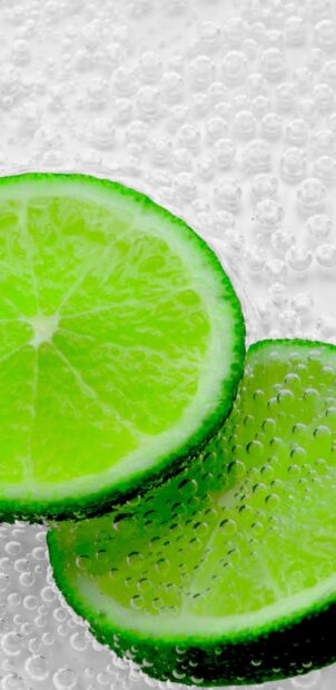 Close up view of lime slices covered in bubbles in sparkling water