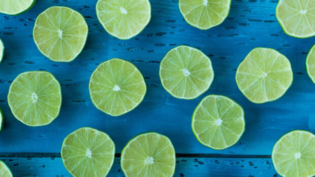 Fresh lime slices arranged on a blue wooden surface with vivid green color