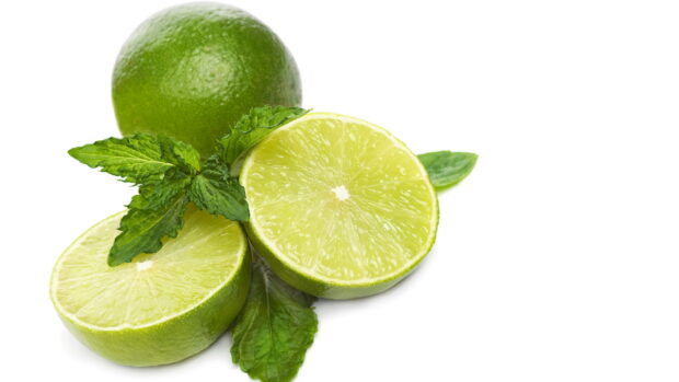 Fresh lime halves with green leaves on a white background