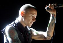 A tattooed musician from Linkin Park performing passionately on stage with a microphone in hand