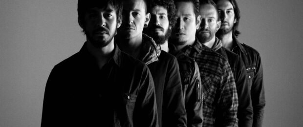 Linkin Park band members standing in a row with serious expressions in a black and white photo
