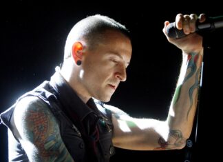 A tattooed musician from Linkin Park performing passionately on stage with a microphone in hand
