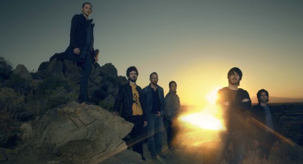 Linkin Park band members standing on rocky terrain at sunset with dramatic lighting