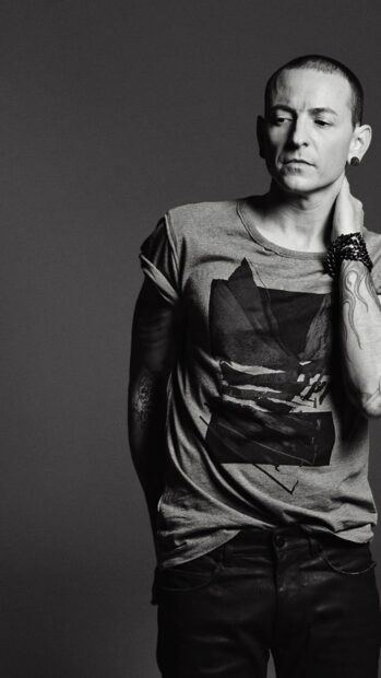 Linkin Park member posing with tattooed arms and wearing a graphic t shirt in black and white