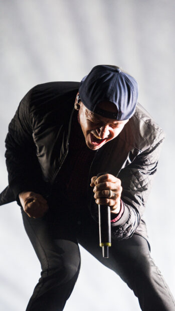 Linkin Park singer performing passionately on stage wearing a cap and black jacket