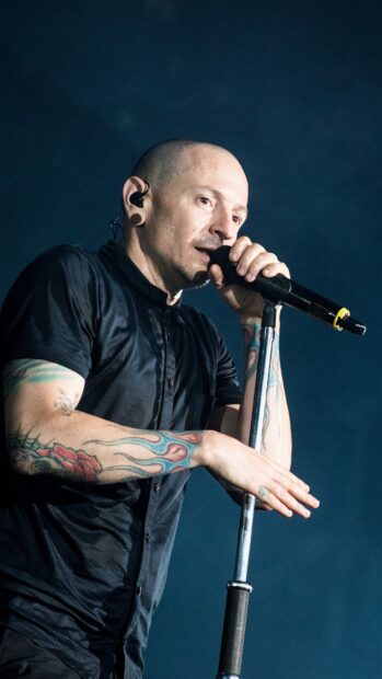 Linkin Park singer performing on stage with microphone and tattoos on arms