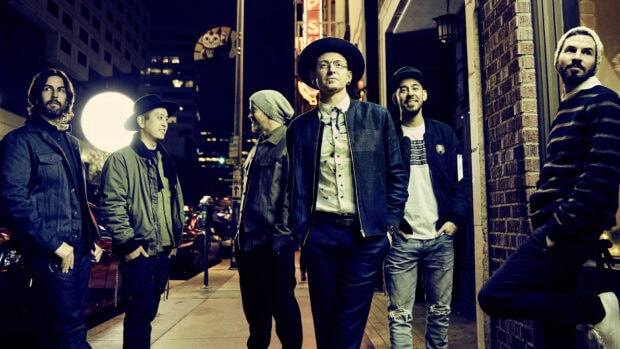 Linkin Park band members standing on a city street at night wearing casual outfits