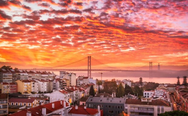 The Lisbon Portugal Wallpapers feature a vibrant sunset over the city with the famous bridge in view, HD Desktop Wallpaper