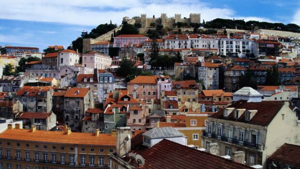 The Lisbon Portugal Wallpapers captures colorful rooftops and castle walls under a blue sky, HD Desktop Wallpaper
