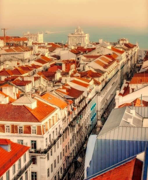 A vibrant Lisbon Portugal cityscape featuring terracotta roofs and historic buildings by the sea, HD Desktop Wallpaper