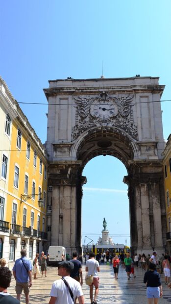 The Lisbon Portugal arch with a clock and tourists walking under it on a sunny day, HD Mobile Wallpaper