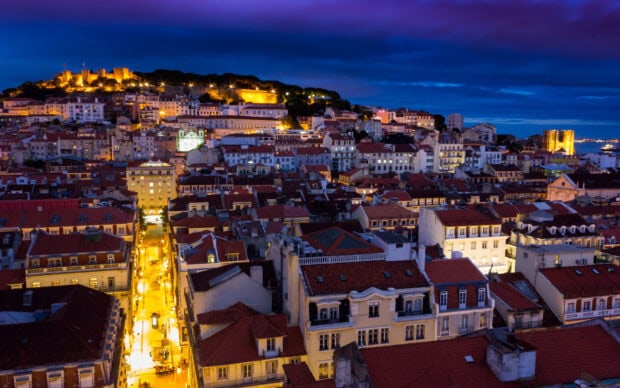 The night cityscape of Lisbon Portugal showcases illuminated streets and historic buildings under a dark blue sky, HD Desktop Wallpaper