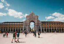 People walking near a historic arch in Lisbon Portugal during the day, 2K Desktop Wallpaper